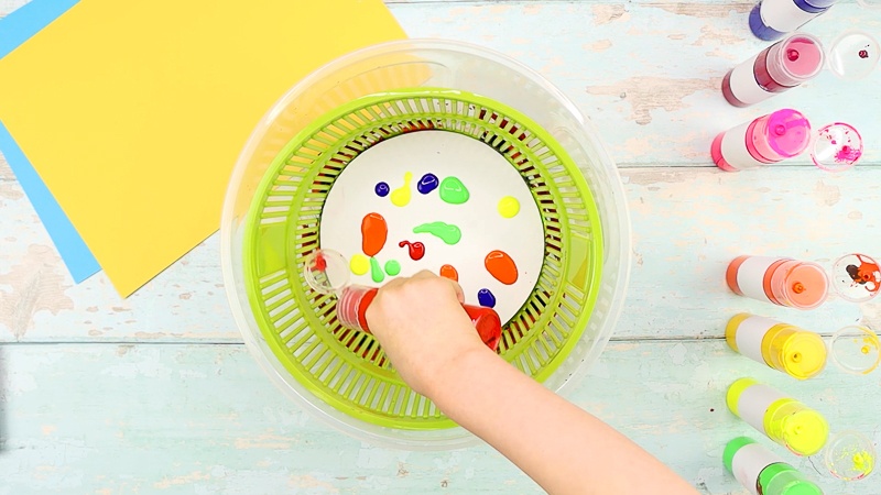 Add paint to the white card stock within the salad spinner. Use lots of different colors.