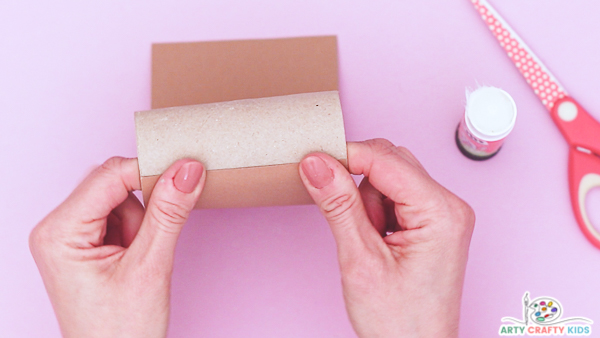 Image showing a hand wrapping brown paper around a paper roll.