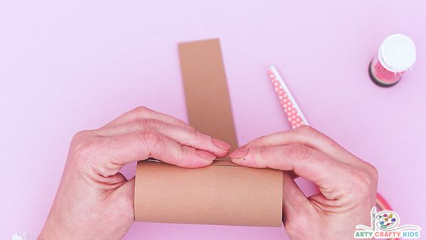 Image showing a hand securing the brown paper to the paper roll.