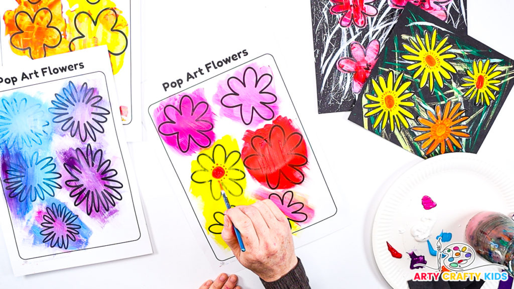 Image of a hand using a paintbrush to paint the center of the flowers, which are pink, yellow and red.