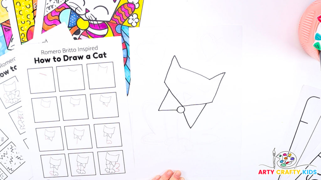 Image of a hand using the how-to-draw step-by-step printable to draw Britto's cat's bowtie.