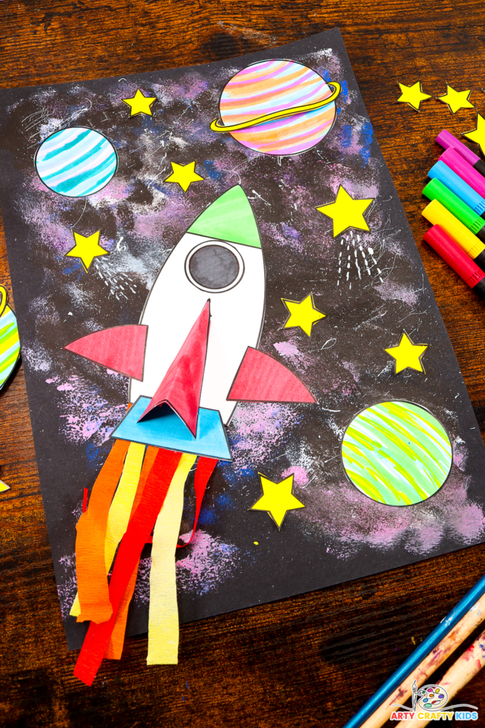 Easy Space art project for kids to make; featuring a rocket ship, planets, and a galaxy-painted background.