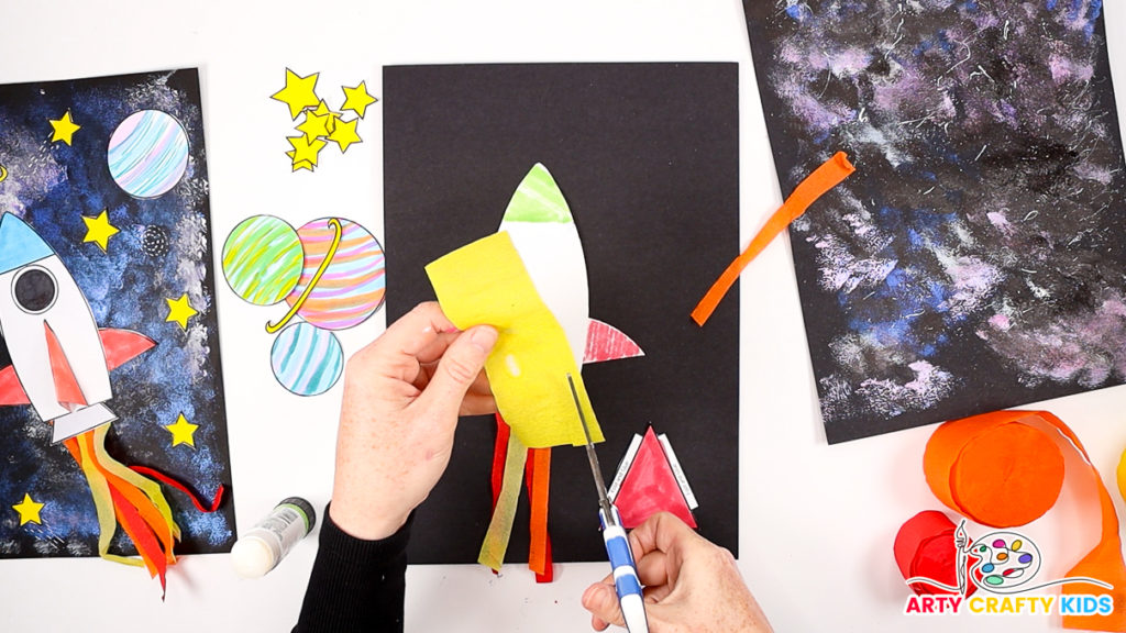 Image of a hand cutting up yellow tissue paper into strips.