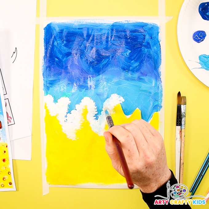 The image shows a hand painting the using a bristle brush to paint white waves.