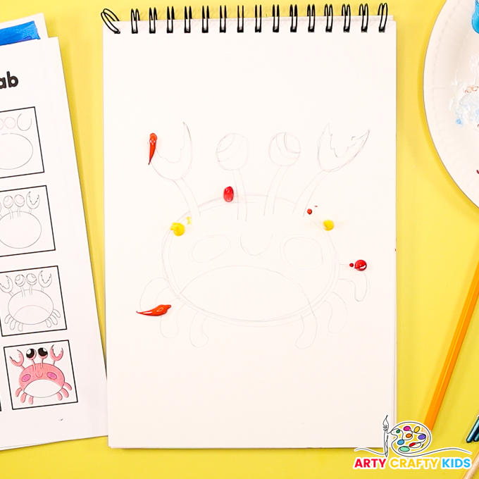 The image shows a pencil-drawn crab surrounded by yellow, orange, and red blobs.