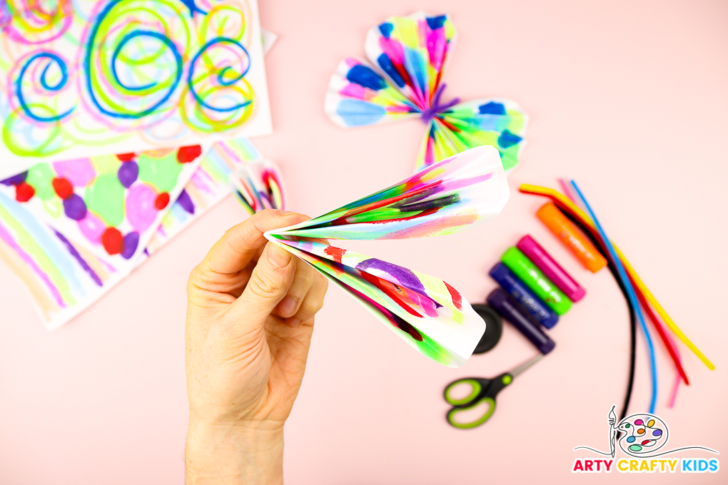 Image of a hand folding one of the wings in half and compacting the folds.