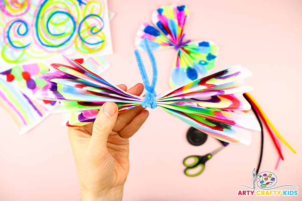 Image of a pipe cleaner wrapped around the papers with two ends sticking up for antenna.