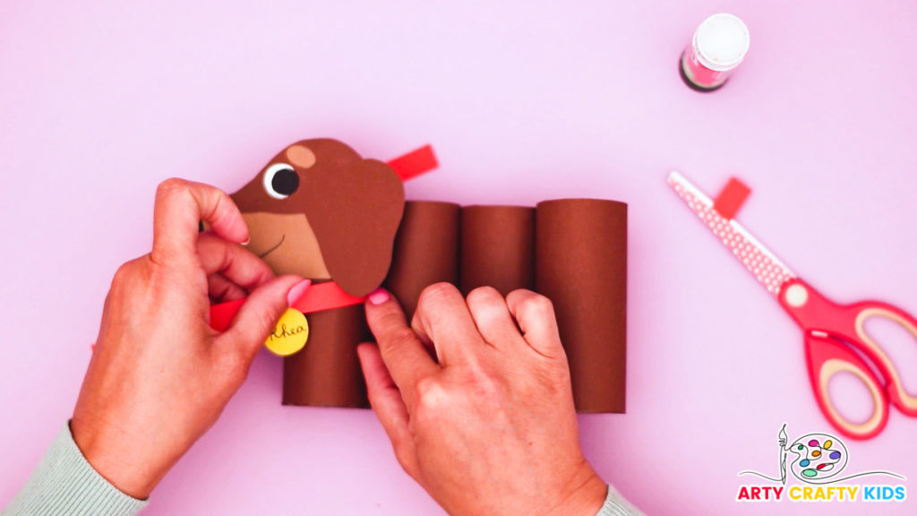 Image of a hand glueing the collar and tag onto the dog pencil holder.