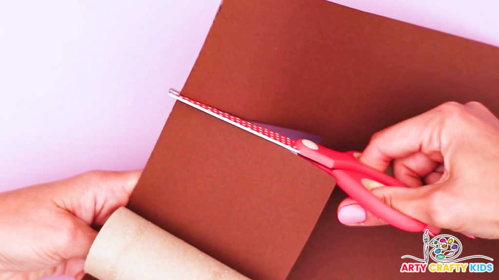 Image of a hand cutting a strip of brown paper to set to wrap around a paper roll.