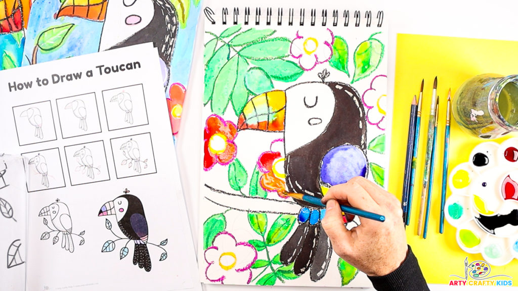 Image featuring a hand painting the toucan and background in colorful shades.