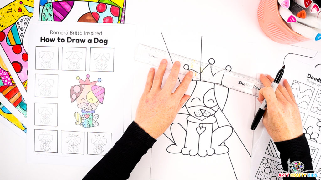 Hand using a ruler and black maker pen to segment the background of the Romero Britto Dog Drawing.