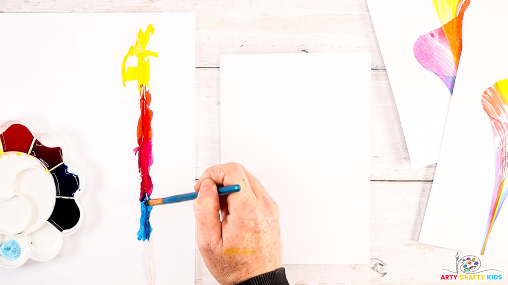 A hand painting the string with watercolor paint.