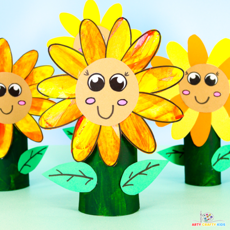 Colorful paper roll sunflower craft surrounded by different sunflowers of varying heights and colors.