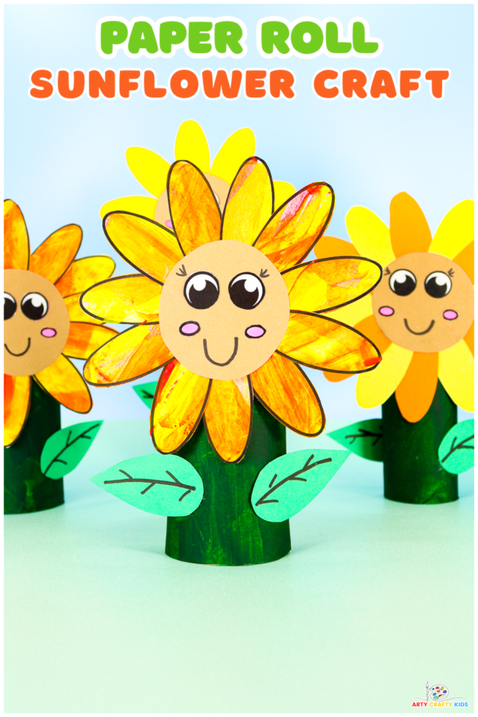 Colorful paper roll sunflower craft made by kids, featuring bright yellow and orange petals, a brown center with a happy smiley face, and green leaves. The craft is displayed on a table, surrounded by sunflowers of varying heights and colors.