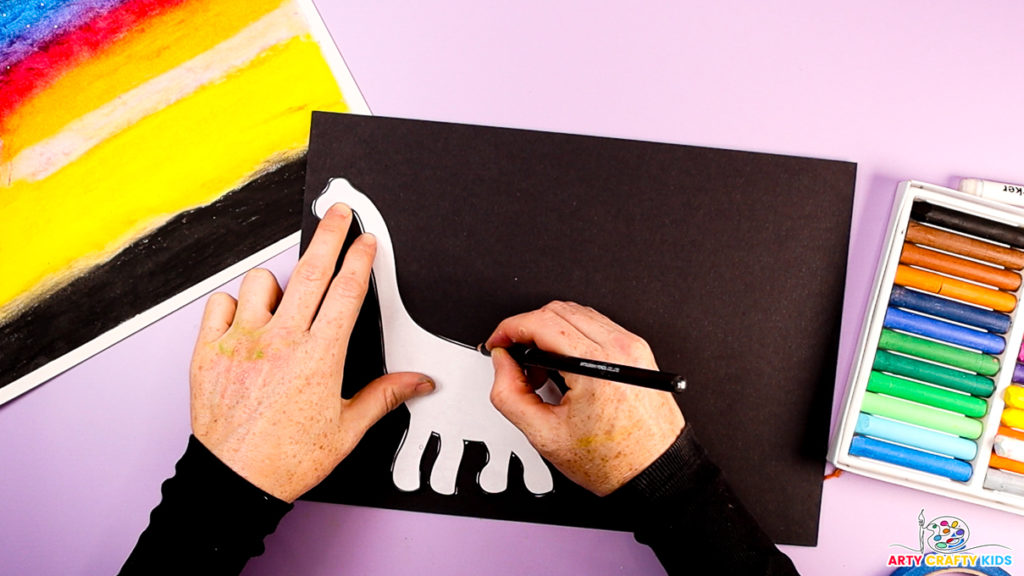 Image of a hand tracing a brachiosaurus dinosaur silhouette onto black paper.