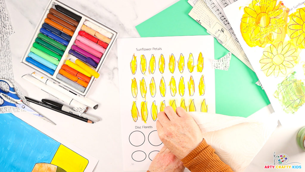 Image of a hand blending the oil pastels with a piece of kitchen towel paper.