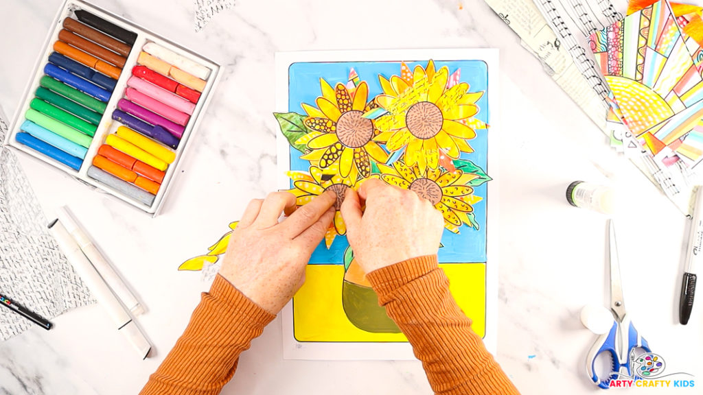 Image of a hand affixing the disc flowers to the centers of the sunflowers to complete the van gogh inspired sunflower painting.