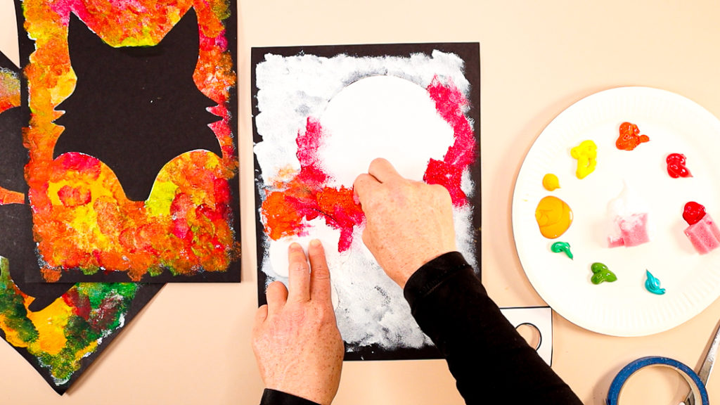 Image of a hand applying red and orange around the edges of the ,mushroom.