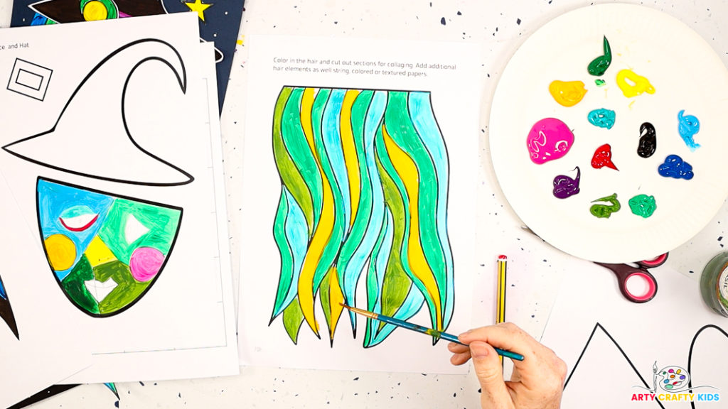 Image of a hand painting the collage hair template. Colors include green, metallic blue and yellow.