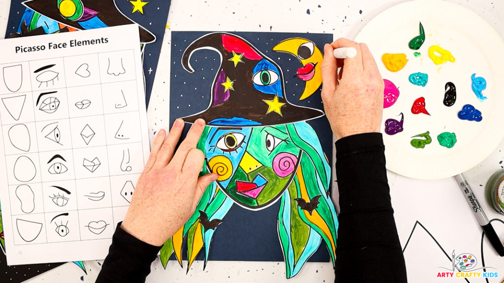 Image of a near completed Picasso Witch Collage Art face - a hand is adding a collection of white dots around the witches head.