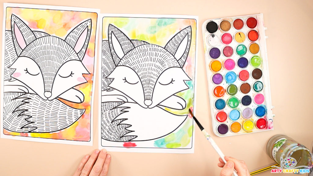 An image shows a hand painting watercolor circles around the fox's body in green, yellow and Autumnal colors.