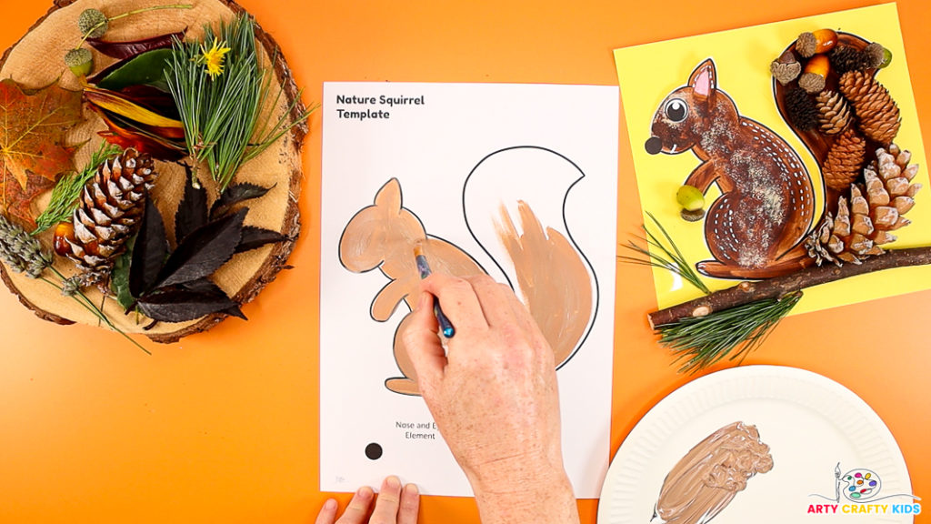 Image of a hand painting a squirrel template a light brown color.