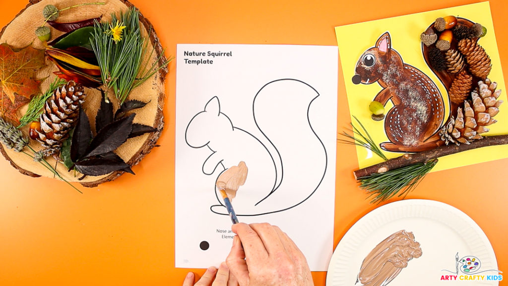 Image of a hand painting a squirrel template a light brown color.