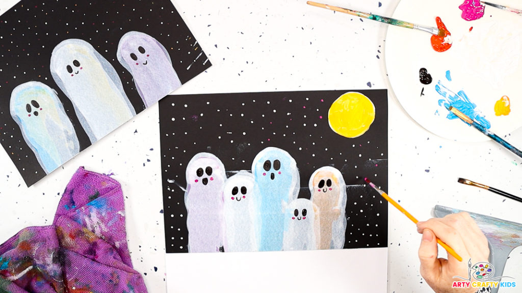 Image of a hand painting tiny white, pink, and yellow dots around the squeegee-painted ghosts.