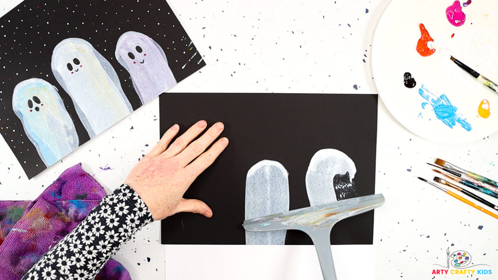 Image of a hand painting a ghost with a squeegee using a wavy scraping motion.