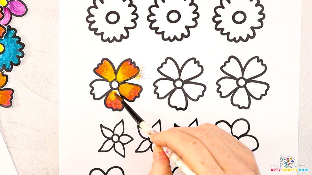 Image of a hand painting the flower orange and yellow.