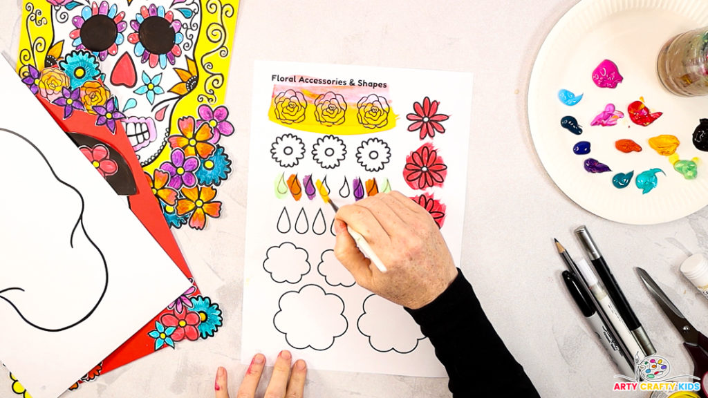 Image of a hand painting the remaining elements off the templates bright and vibrant colours.