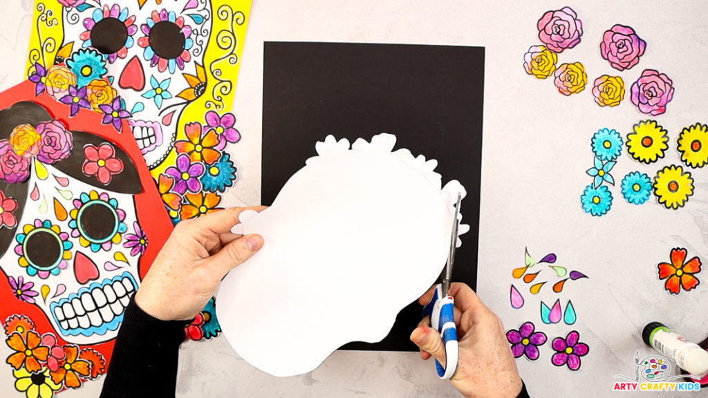 Image of a hand cutting off the excess flowers from around the skull to help define the skull shape.