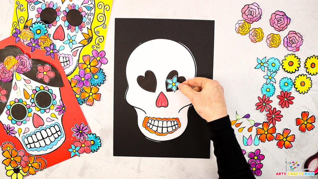 Image of a hand arranging the mouth, nose and eye elements onto the sugar skull.