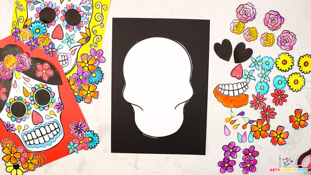 Image of a skull cut-out placed on black card stock with surrounding cut-out elements of flowers, hearts, teeth, and more.