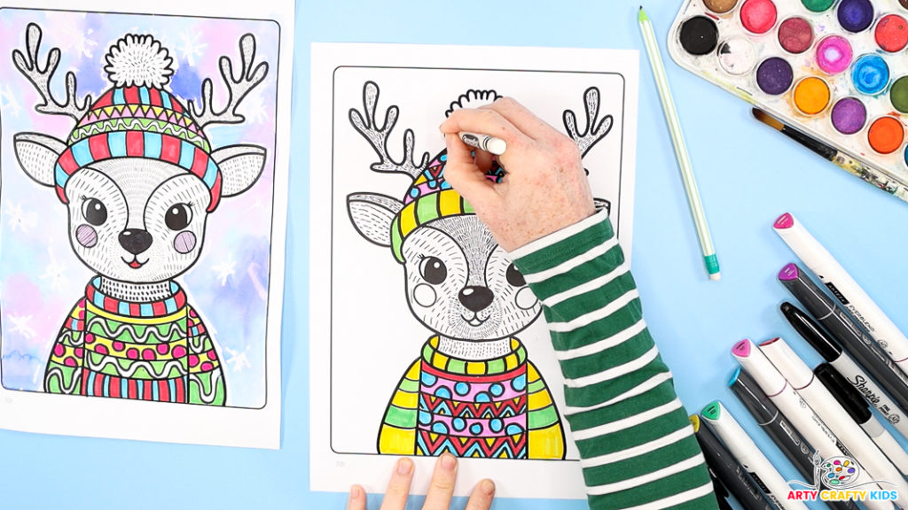 Image of a hand outlining the completed reindeer line art with a white wax crayon.