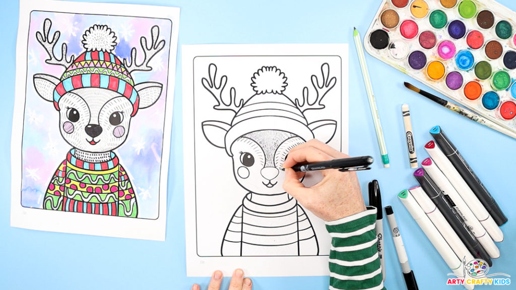 Image of a hand drawing small vertical black lines around the reindeer's eyes.