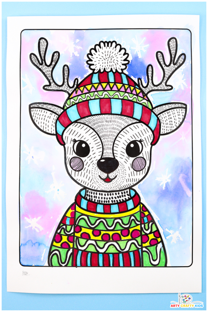 Illustrated reindeer line art project for kids featuring a festive design with a colorful Christmas sweater and bobble hat. The reindeer is surrounded by a wintery watercolor background with soft blue, purple, and pink hues, accented by wax-resist snowflakes.