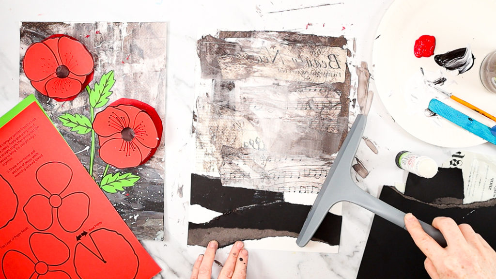 Image features a hand scraping the paint across the paper with a squeegee tool.