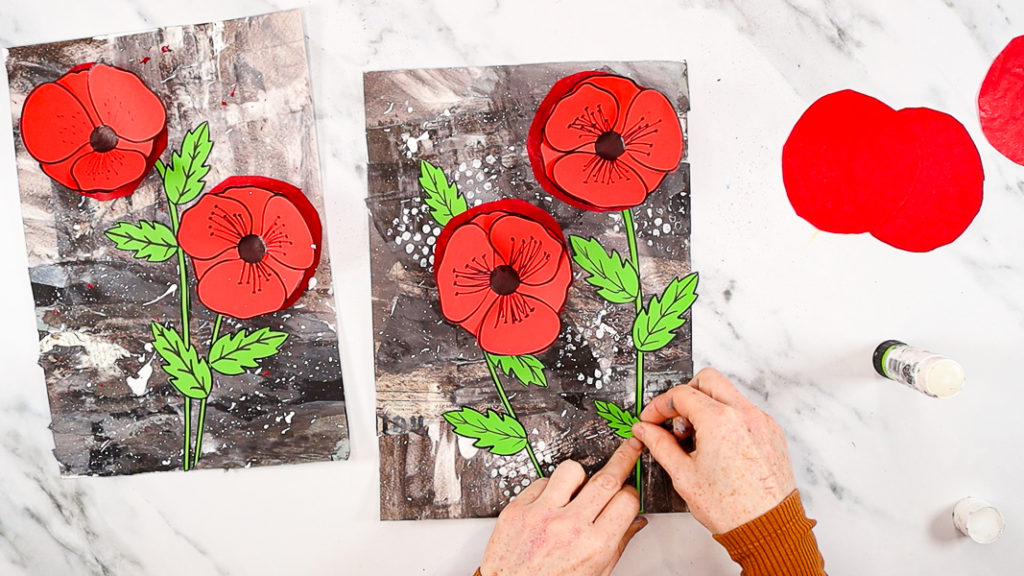 Image of a hand attaching the remaining leaves to the poppy stems.