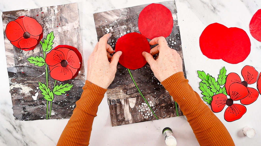 The image features a hand gluing large red tissue paper circles to the top of each stem.