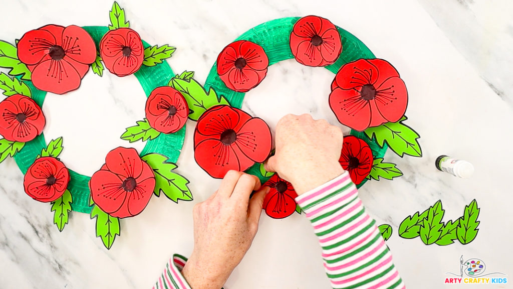 Image featuring a hand gluing the leaves around the poppies.