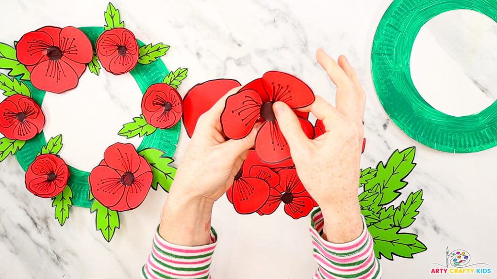 Image featuring a hand gluing the top poppy within the base layer.