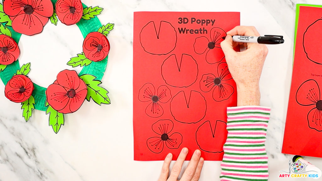 Image of a hand drawing poppy seeds onto the flowers of the poppy template.