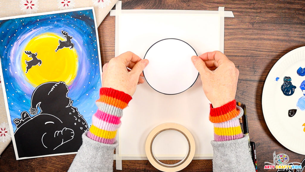 The image features a pair of hands positioning a large white circle onto the canvas, which has masking tape around its borders.