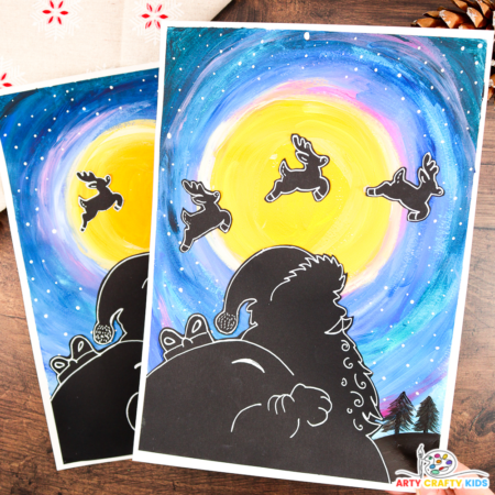 A festive Santa silhouette art project featuring a glowing yellow moon, a vibrant blue and purple night sky, and reindeer silhouettes flying across the moon. The artwork includes fine details and is surrounded by rustic pinecones for a cozy holiday feel. Perfect for Christmas crafts with kids.