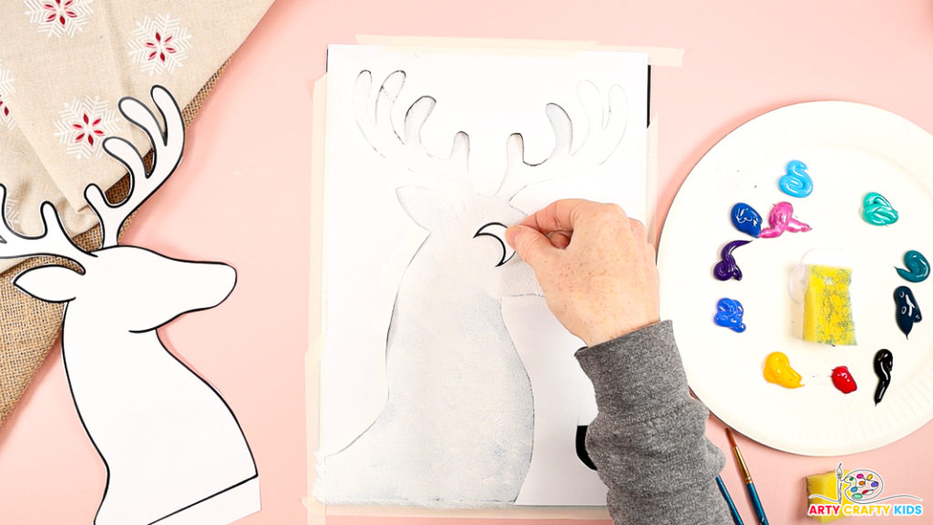 The image features a hand adding a moon to the newly painted white reindeer.