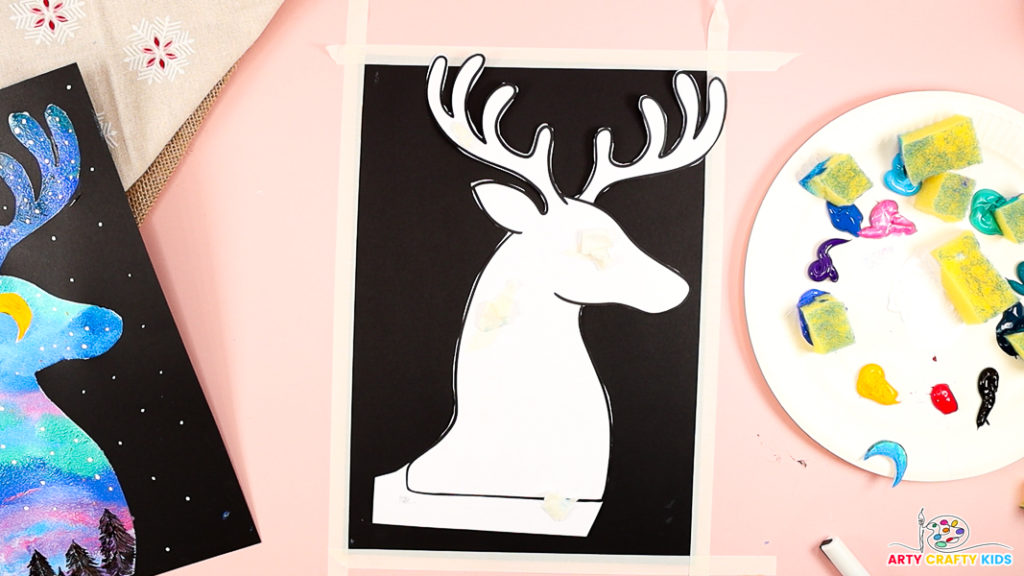 Image features a sheet of black card stock and a white reindeer template.