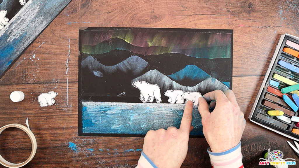 Image of a hand affixing a family of polar bears to complete the Chalk Pastel Polar Bear Art.