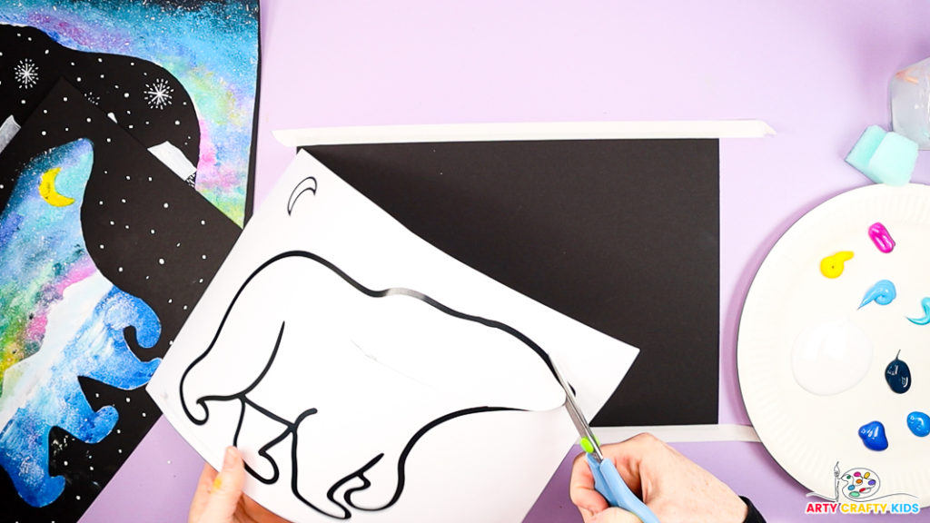 Image featuring a hand cutting out the polar bear silhouette.