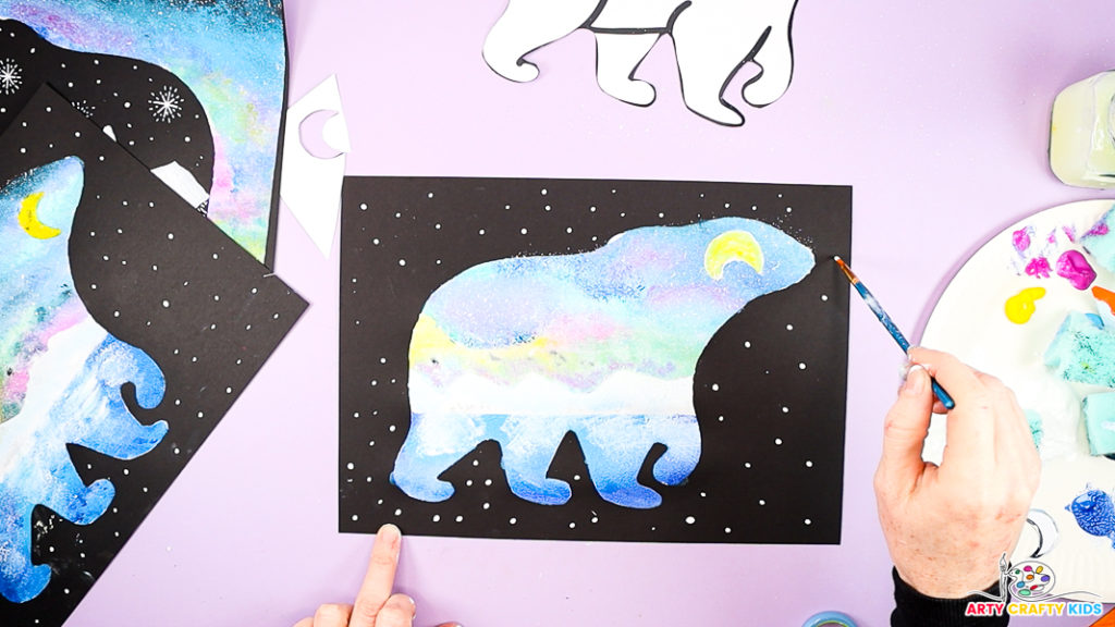 Image of a hand painting white twinkly stars around the silhouette of a polar bear.